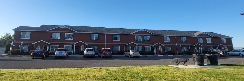 A red brick building with a parking lot in front.