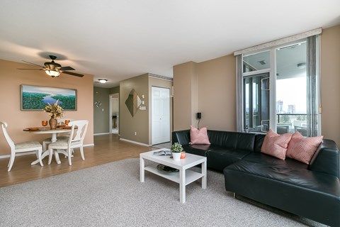 A living room with a black couch and a white coffee table.