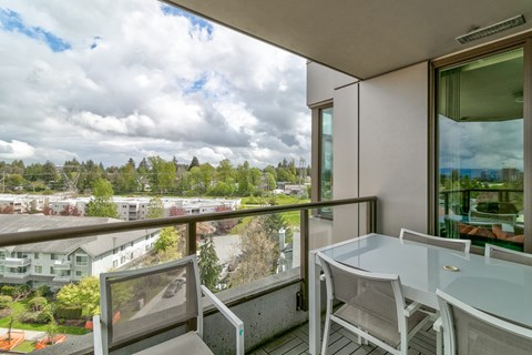 A balcony with a table and chairs overlooking a residential area.