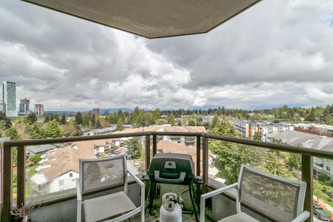 A balcony with two chairs and a table overlooking a residential area.