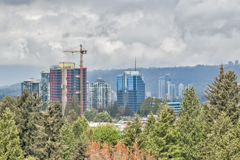 A cityscape with a crane on a building under a cloudy sky.