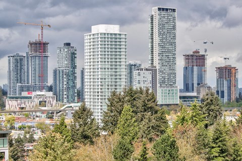 A cityscape with tall buildings and construction cranes.