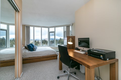 A room with a bed, desk, and chair.