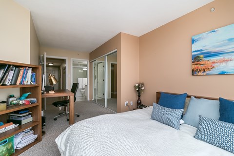 A bedroom with a bed, desk, chair, and bookshelf.