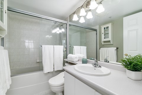 A white bathroom with a toilet, sink, and mirror.