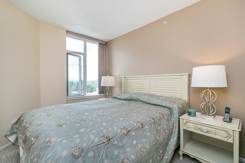 A bedroom with a bed, nightstand, and window.