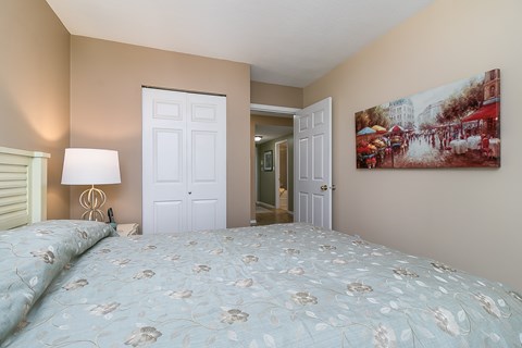 A bedroom with a bed, lamp, and painting on the wall.