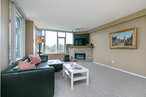 A living room with a black couch, a white coffee table, and a painting on the wall.