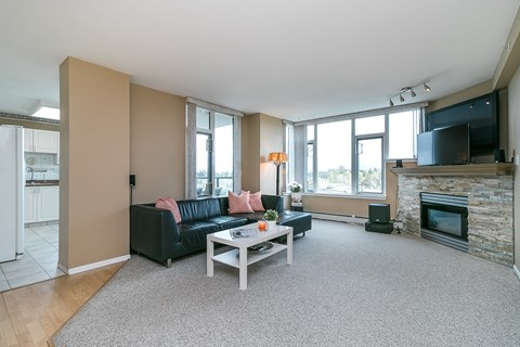 A living room with a black couch and a fireplace.