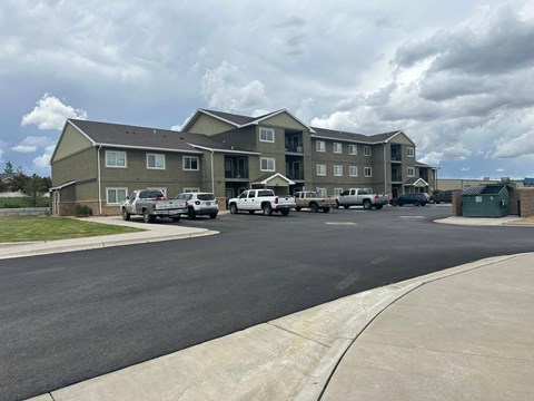 A large apartment complex with a parking lot in front.