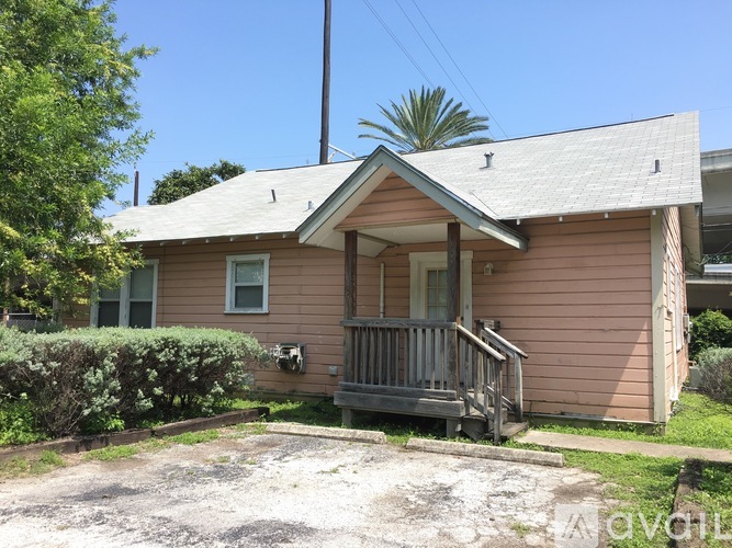 A small house with a porch and a driveway in front.