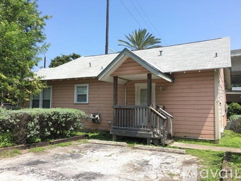A small house with a porch and a driveway in front.