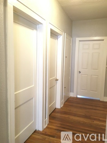 A hallway with white doors and wooden floors.