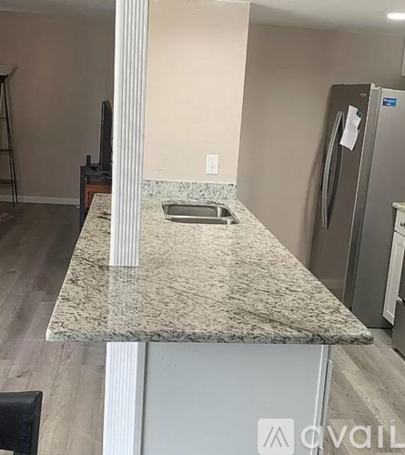 A kitchen counter with a granite top and a refrigerator in the background.