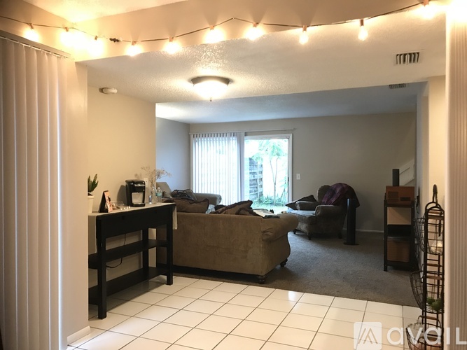 A living room with a couch, a chair, a coffee table, and a window with blinds.