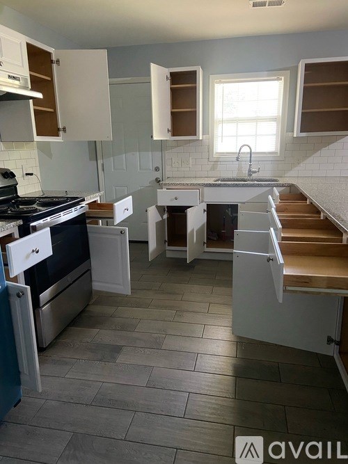 A kitchen with a stove, sink, and cabinets.