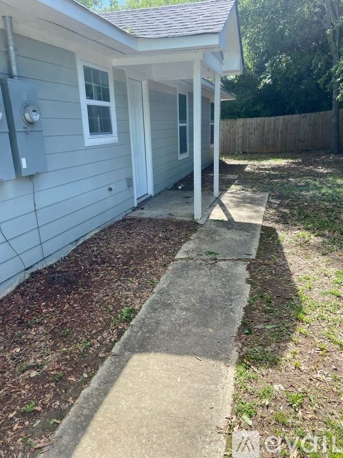 A small house with a grey siding and a white door.