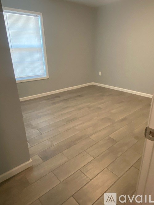 A room with wooden flooring and a window with blinds.