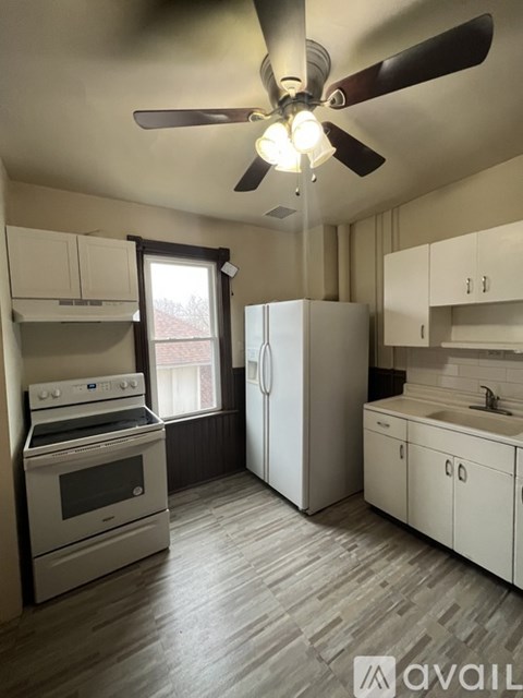 A kitchen with a white stove, refrigerator, and cabinets.