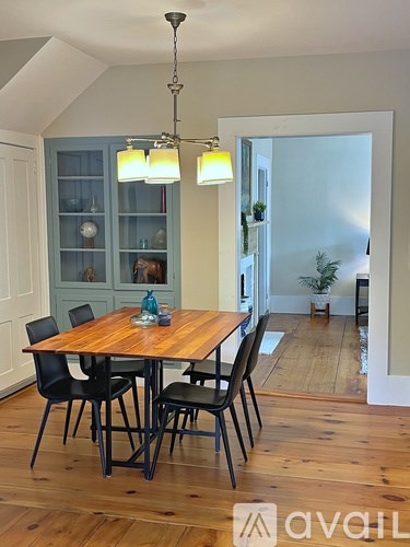 A wooden dining table with four chairs and a hanging light fixture.