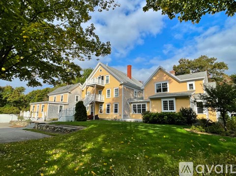 A large, two-story house with a yellow facade and a red door.