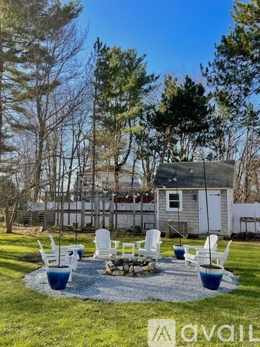 A backyard with a fire pit and chairs.