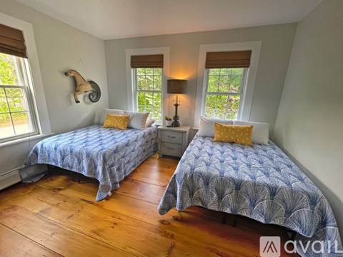 Two twin beds with blue bedspreads in a room with wooden floors.