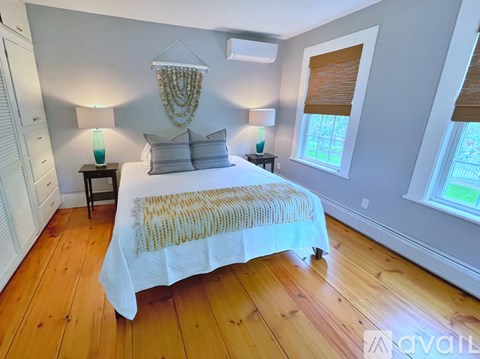 A bedroom with a large bed and a window with blinds.