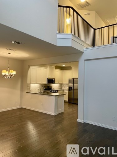 A modern kitchen with a wooden floor and a chandelier.