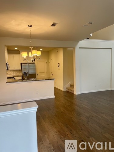 A modern kitchen with white cabinets and a wooden floor.