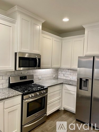 A kitchen with white cabinets and a stainless steel refrigerator.