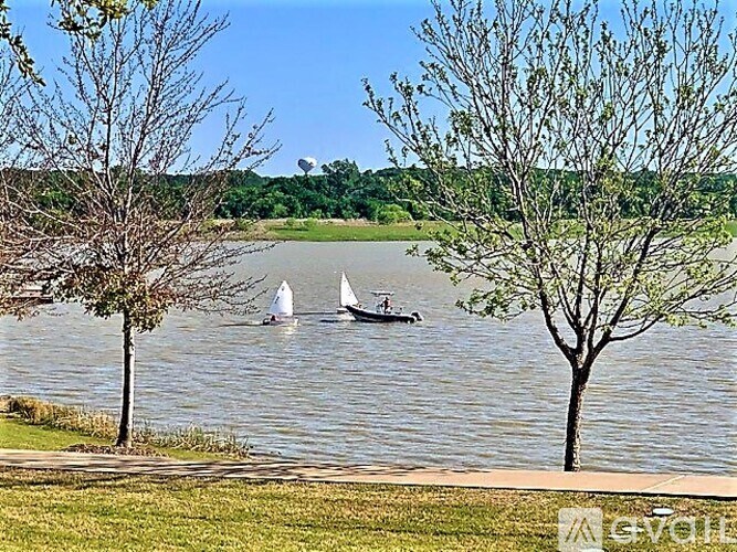 A serene lake with two sailboats and a person rowing a boat.