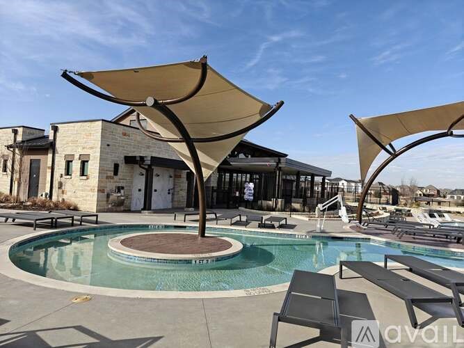 A pool area with sun shades and lounge chairs.