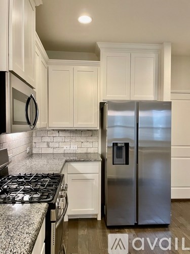 A kitchen with a stainless steel refrigerator and a black microwave.