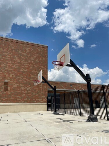 A basketball hoop stands in front of a brick building.