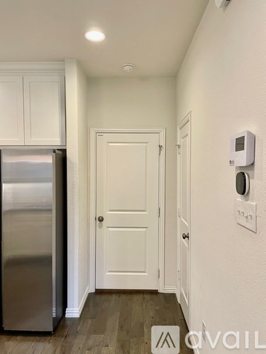 A kitchen with a stainless steel refrigerator and a white door.