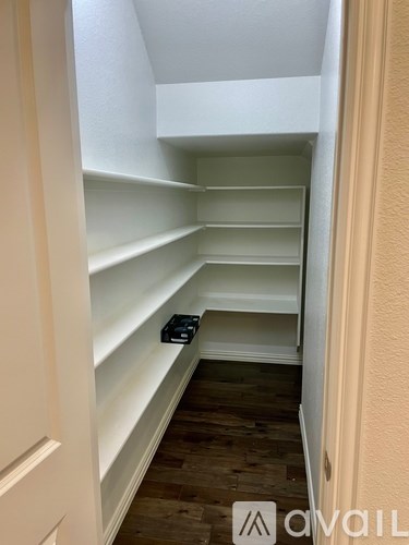A narrow hallway with white shelves and a wooden floor.