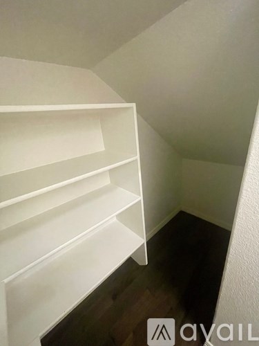 A white shelving unit in a room with wooden flooring.