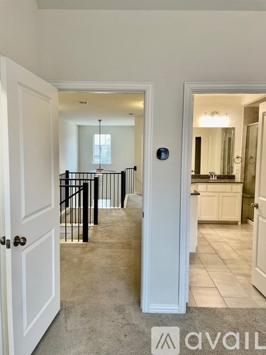 A hallway with a black railing and white doors.