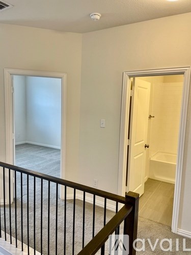 A room with a white door and a window with a view of the hallway below.