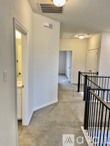 A hallway with a carpeted floor and white walls.
