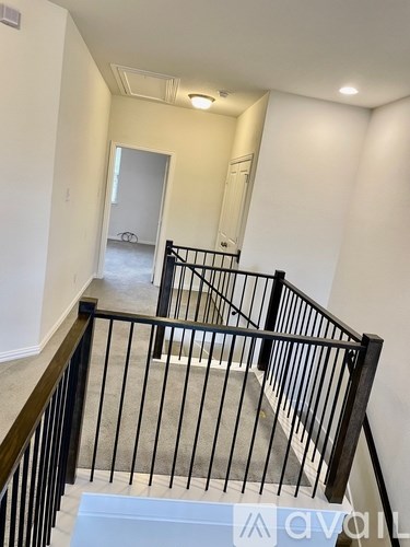 A staircase with a black railing and a white landing.
