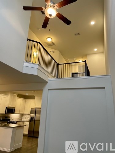 A modern kitchen with a stainless steel refrigerator and a ceiling fan.