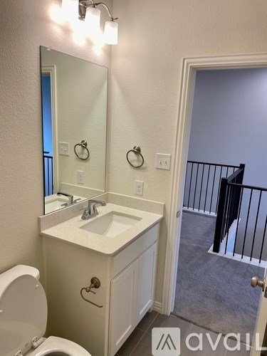 A bathroom with a toilet, sink, mirror, and light switches.