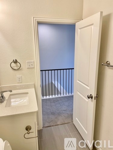 A bathroom with a toilet, sink, and a door leading to a balcony.