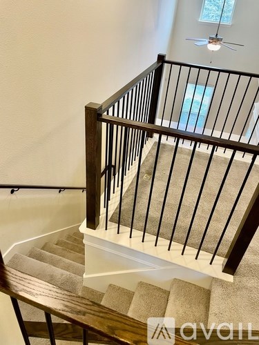 A staircase with a black railing and beige carpeted steps.