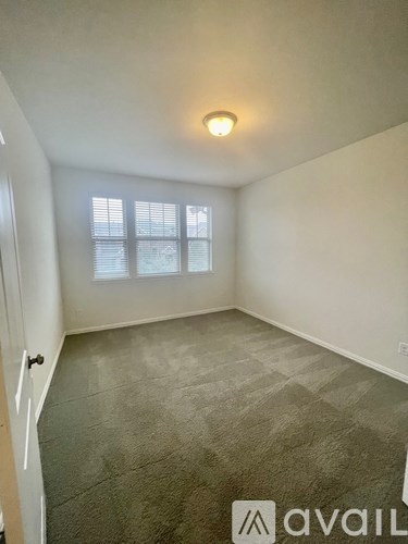 A room with a carpeted floor and a window with blinds.