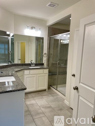 A bathroom with a sink, mirror, and shower.