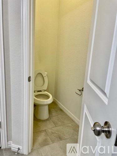 A white toilet is in a small bathroom with yellow walls.