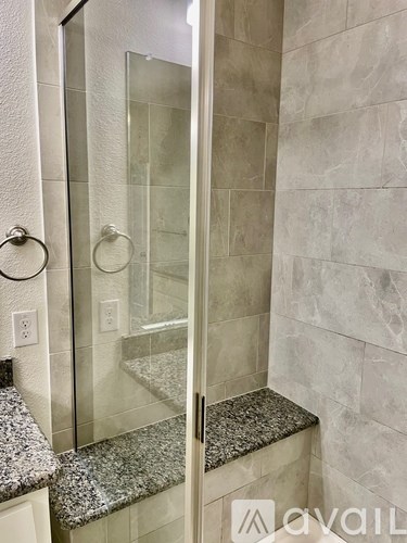 A bathroom with a granite counter top and a walk in shower.
